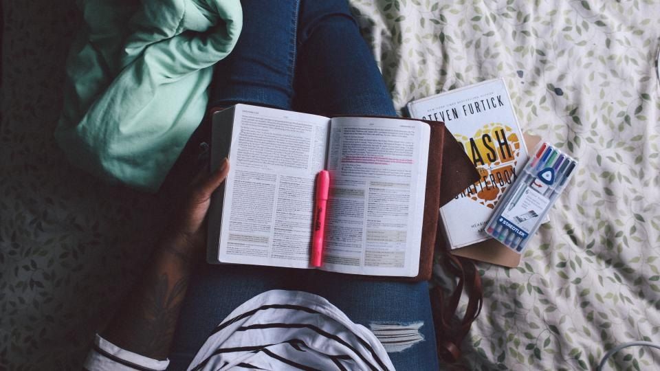 A student reading an open textbook with notes beside it
