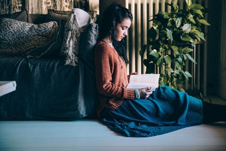 A student reading notes while sitting on the floor at home